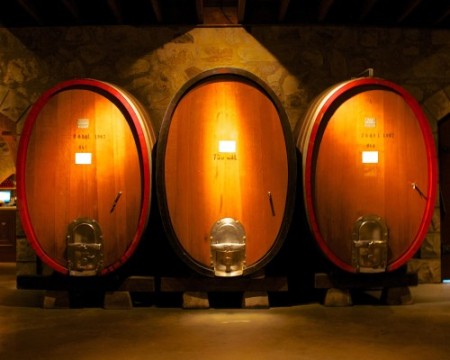Three wooden barrels in a room with lights on.